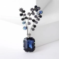 Detailed macro view of an elegant floral brooch with large emerald-cut blue crystal and rhinestones - Blue
