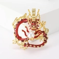 Close-up of golden dragon brooch with red enamel details and white pearl accent - Red