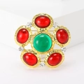 Macro shot of flower brooch with green center stone and red gemstones on gold metal - Red And Green Glass White Rhinestone