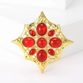Nahaufnahme der goldenen Vintage-Brosche mit achtstrahligem Stern und roten Glassteinen - Rotes Glas
