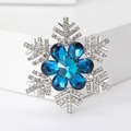 Macro shot of silver snowflake brooch with blue crystals and transparent rhinestones - Blue