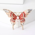 Primer plano detallado de un broche de mariposa de metal dorado con esmalte rojo y cristales - Rosa (MM-BR-PK-3872)