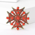Detail einer Vintage-Kreuzbrosche mit antikgoldener Basis und roten Perlenbesatz - Rot