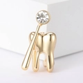 Detalle de un broche de diente dorado y espejo dental con una piedra de circón brillante - Dorado