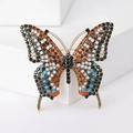 Detailopname van vintage vlinderbroche met kleurrijke strasstenen op witte display - Donkere Koffie Veelkleurig