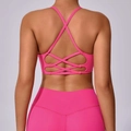 Detail eines pinken Yoga-BHs mit komplexem Überkreuz-Design am Rücken für Fitness - Fuchsia