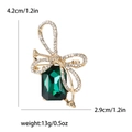 Bowknot brooch with white rhinestones and large emerald green gemstone in gold finish - Green