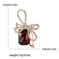 Elegant gold bow brooch with white rhinestones and a large deep red rectangular crystal - Purple