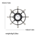 Dettaglio spilla a timone nautico con perla centrale e strass neri, diametro di 4cm - Argento