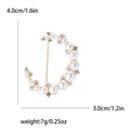 Elegante spilla a mezzaluna dorata con perle bianche e cristalli su sfondo bianco - Oro