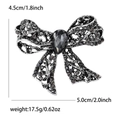Vintage alloy hollow bow brooch with black rhinestones and large drop-shaped center stone - Black