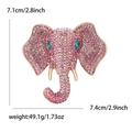 Exaggerated golden elephant brooch with pink rhinestones and green gem eyes on white background - Pink