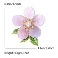 Detail view of cherry blossom enamel brooch with pearl center and green leaves - Purple