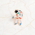 Detailed close-up of white astronaut enamel pin with gold plating on marble surface - Astronaut Style (XZ1122)