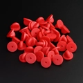 Macro shot of 30 red rubber clutch backings for pins on a textured black surface - Red
