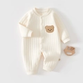 Close-up of cream quilted cotton baby romper with brown bear patch and side tag detail - Thermal Beige Embroidered Bear Romper
