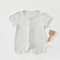 Close-up of soft breathable baby romper with snap buttons and wooden bear rattle accessory - Bean Green