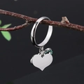 Silberner Infinity-Herzring mit grünen Kristallen vor rustikalem Zweig-Hintergrund - Doppelherz Unendlichkeitssymbol Strass-Stil (EJZ061)