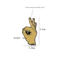 Macro detail of OK hand gesture enamel pin showing dimensions 3.3cm by 1.9cm and yellow finish - Funny Gesture (CC251)