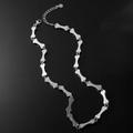 Collana a maglie a forma di osso in acciaio argentato su superficie nera riflettente - Collana a Osso Piccolo