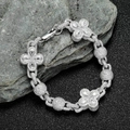 Detailed view of silver clover bracelet with sparkling zircons on black sand background - 7 inches / Platinum