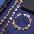 Dettaglio di un set di gioielli d'oro con gemme colorate e croci su tessuto blu - Collana da 24 pollici / Oro