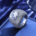 Makroaufnahme des Iced-Out-Rings mit großem Zirkon und Mikro-Pave-Diamanten auf blauer Seide - US 7 / Platin
