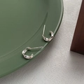 Minimalist S999 sterling silver Mobius C-shaped hoop earrings on a ceramic dish - 990 Silver / Silver