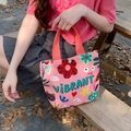 Pink canvas tote bag with cartoon vibrant prints and orange handles in a park setting - Colorful Cute Things