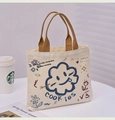 Detail of canvas tote bag featuring blue cloud graphic and brown woven handles - Sunflower Cloud Print / Off White