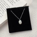 925 sterling silver opal necklace with an oval gemstone and wavy metal edge on a black base - Silver