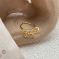 Elegante anillo de lazo dorado con dijes esféricos sobre fondo con textura neutra - Abierto Ajustable / Dorado
