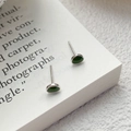 Minimalistische S999 Silber grüne Avocado Ohrstecker auf einem alten offenen Buch - Silber