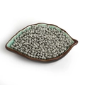 Primer plano de pequeñas cuentas de hierro plateadas para joyería en un plato de cerámica - Diámetro 2.4mm Apertura 0.6mm Aprox 1000uds/Pack / Oro blanco