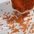 Macro shot of transparent orange glass seed beads for DIY jewelry and handmade crafts - Orange Red