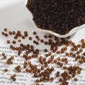 Macro detail of amber brown transparent glass seed beads for DIY jewelry and sewing - 2mm / Dark Coffee
