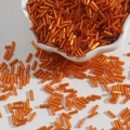 Vibrant orange glass bugle beads in a ceramic bowl for DIY jewelry making and embroidery - Size 3 Bugle 2x7mm / Orange Red