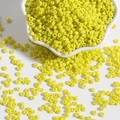 Polished lemon yellow glass seed beads in a white bowl for DIY jewelry making - Yellow