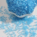 Light blue iridescent glass bugle beads in a ceramic dish for DIY jewelry making - 2mm 15g/Pack Approx 700pcs / Lake Blue
