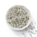 High-shine silver twisted glass bugle beads in a ceramic bowl for DIY jewelry making - Silver