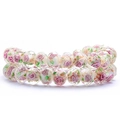 Macro view of faceted glass beads with pink rose patterns, gold foil and green leaves - Pink