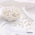 Macro shot of 7x8mm irregular pebble-shaped faux pearl beads on white satin - Bean