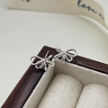 Macro shot of silver bow stud earrings with polished S925 hallmark on a wooden box - Silver
