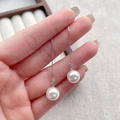 Eleganti orecchini a filo in argento sterling S925 con perle bianche mostrati sulla mano - Perno in argento 925 / Perla di circa 10mm (YC58)