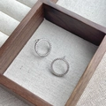 Elegante S925 sterling zilveren oorringen met pavé zirkonia op een donkerhouten display - 925 zilver / Witgoud