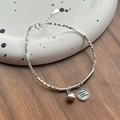 S925 Sterling Silber Armband mit Glücksmünze und Glöckchen auf Vintage-Holzhintergrund - Glück-Tag Armband / 925er Silber