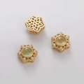 Vista detallada de cuentas de estrella doradas con gema verde y perlas para joyería DIY - Flor Hexagonal Calada con Vidrio Verde Claro Incrustado / 12x13mm (1 Pieza/Paquete) / Dorado