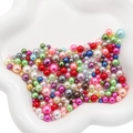 Perlas de ABS de colores vibrantes en un plato de cerámica blanco para manualidades - Multicolor