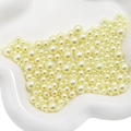 Perlas de ABS crema de varios tamaños en bandeja de cerámica blanca para manualidades - Amarillo claro