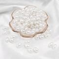 Elegant white oval faux pearl beads for jewelry making displayed on a ceramic plate - Oval Bead / 8x11mm 50 Pieces/Pack / White